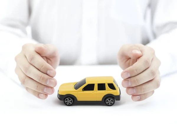 Koncepcja Ubezpieczenia Samochodu Żółtą Zabawką Samochodową Objętą Rękami — Zdjęcie stockowe