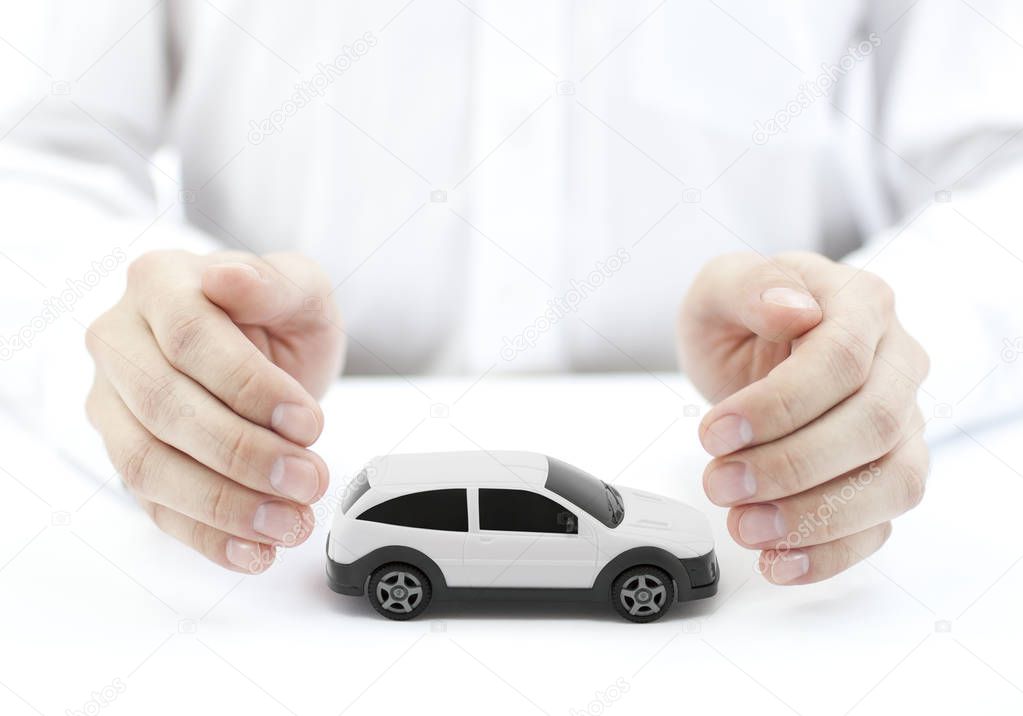 Car insurance concept with white car toy covered by hands 