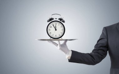 Gümüş tepside eski tarz çalar saat sunan işadamı 