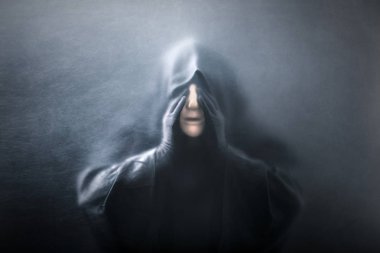 Tozlu bir camın arkasındaki hayalet figürü. Elinde manken kafası olan korkunç bir figür. 