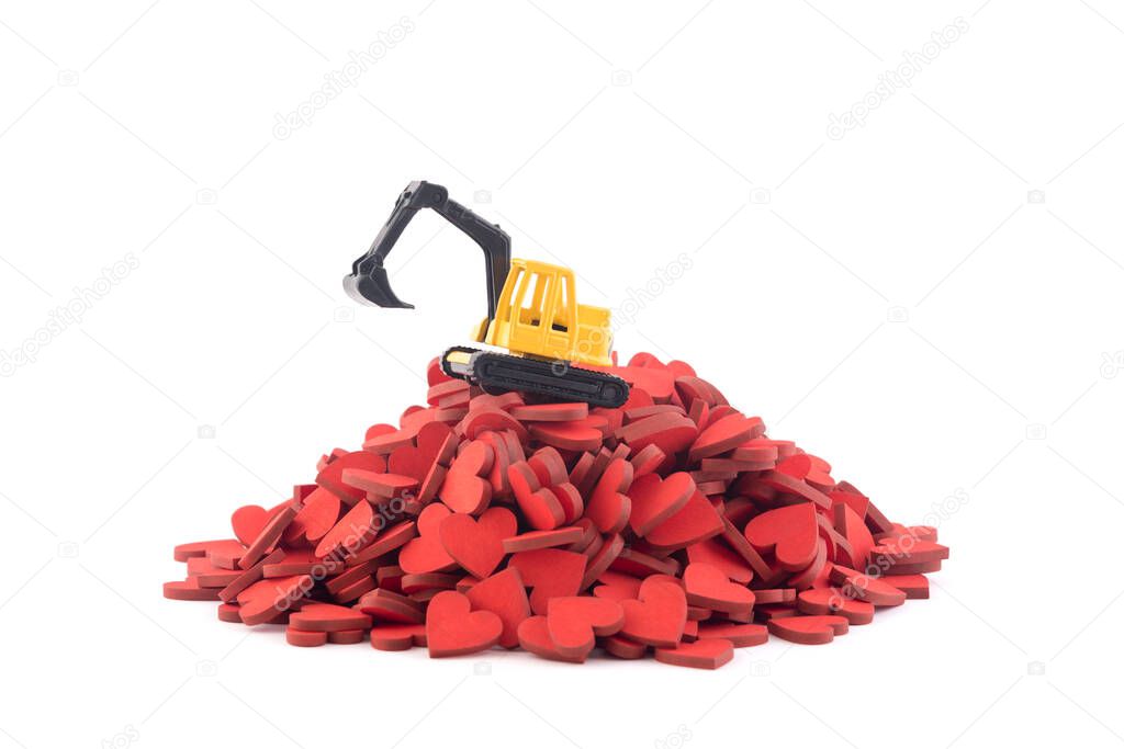 Excavator working on pile of hearts isolated on white background with clipping path