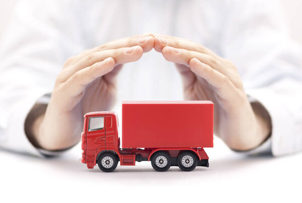 Red cargo delivery truck miniature protected by hands