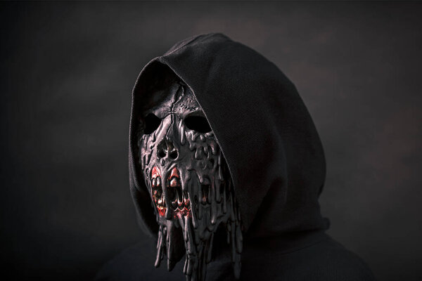 Scary figure in hooded cloak with mask