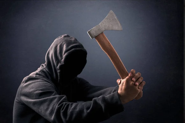 Hooded man with an axe in the dark