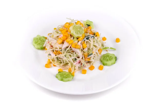 Salad of crab sticks, corn and cucumbers on a white plate isolated over white