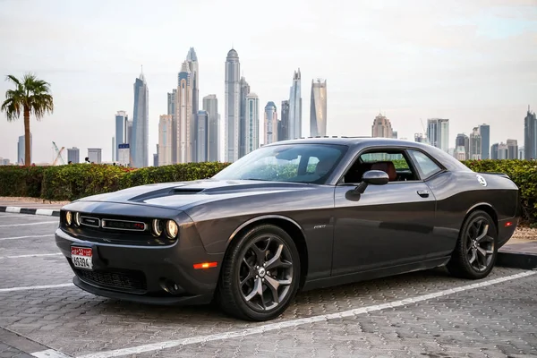 Dubai, UAE - November 16, 2018: Black sportscar Dodge Challenger in the city street at the background of skyscrapers.