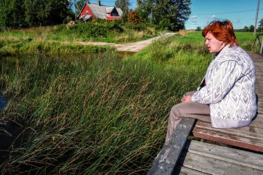 Orta yaşlı kadın bir ahşap köprü nehir kıyısında dinlenme