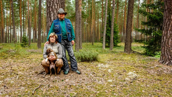 中年夫妇与狗走在树林里 — 图库照片