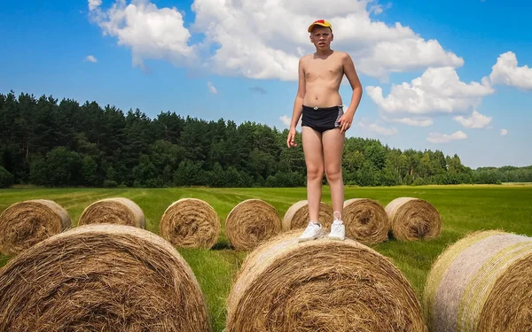 The guy in the yellow cap resting on a bale — Stock Photo, Image