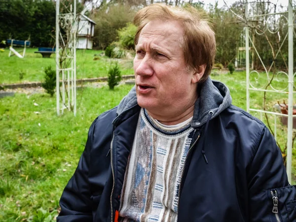 En ældre mand i en jakke hviler i parken - Stock-foto