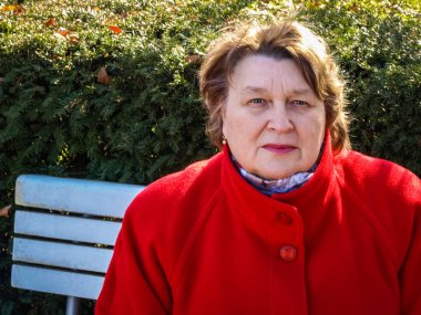 Orta yaşlı kadın parkta bir bankta oturan