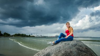 Büyük bir taş üzerinde kırmızı uzun saçlı bir kız tırmandı 