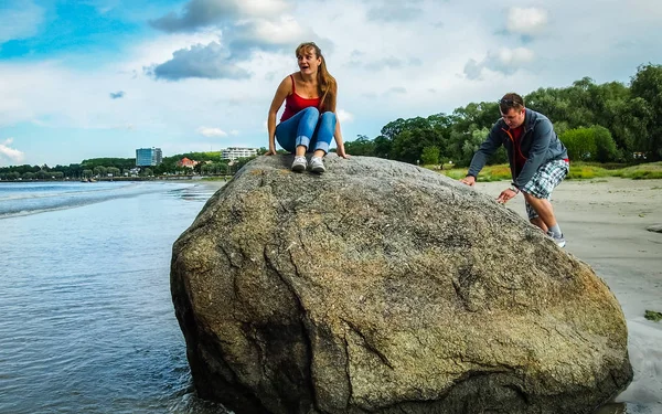 Ein Mädchen lädt einen Kerl ein, auf einen Stein zu klettern — Stockfoto