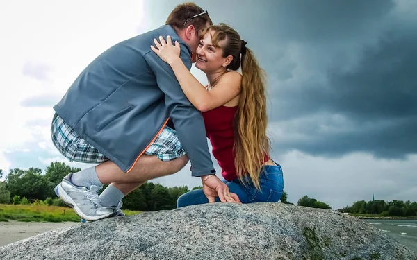 Meisje in rood en guy zoenen op een grote rots — Stockfoto