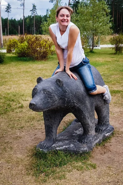 Girl sitting on a statue of a bear — Stock Photo, Image