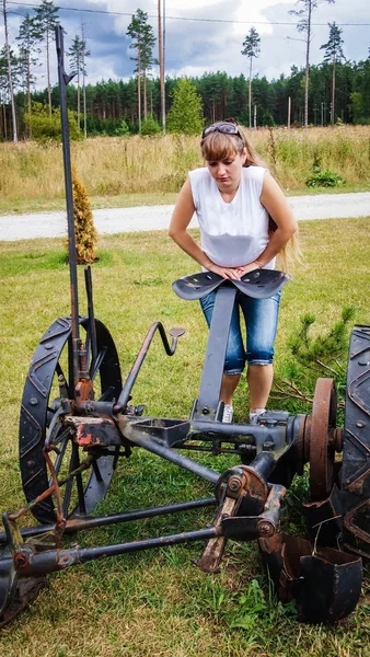 Girl standing at the old agricultural equipment — Stock Photo, Image