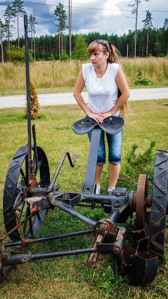 Девушка, стоящая у старой сельскохозяйственной техники — стоковое фото