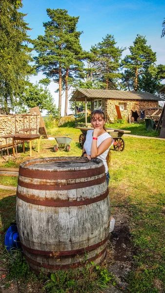 Fille debout à un vieux tonneau rouillé — Photo