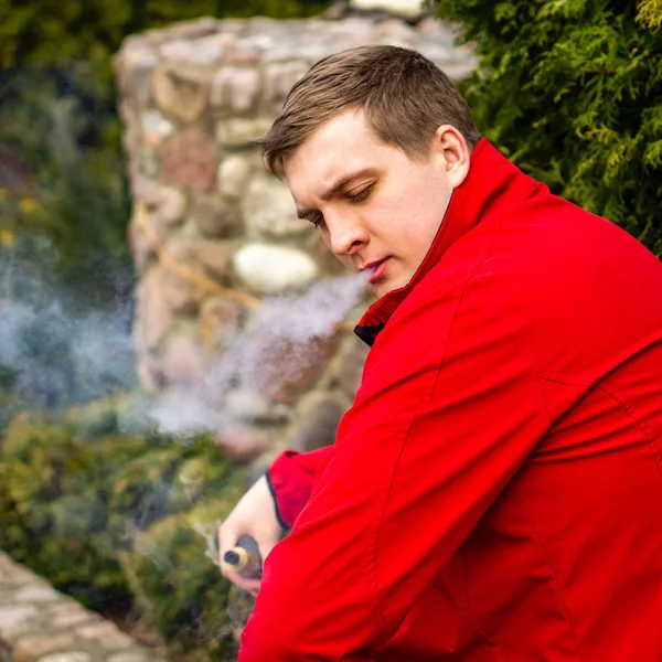 Genç bir adam elektronik sigara içiyor. — Stok fotoğraf
