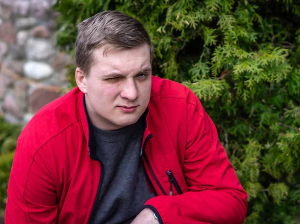 Un jeune homme en veste rouge fume une cigarette électronique — Photo