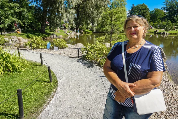 Stará žena odpočívá v městském parku — Stock fotografie