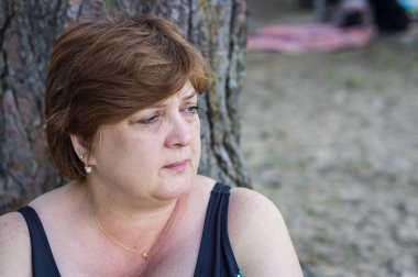 Göl kenarında sahilde dinlenen olgun kadın. 