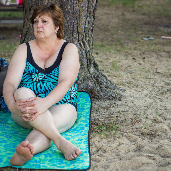Зрелая женщина отдыхает на пляже у озера
. 