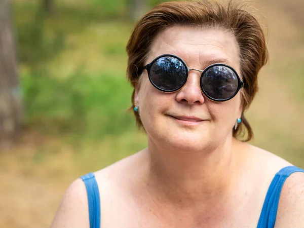 Rijpe vrouw rustend op het strand aan het meer. — Stockfoto