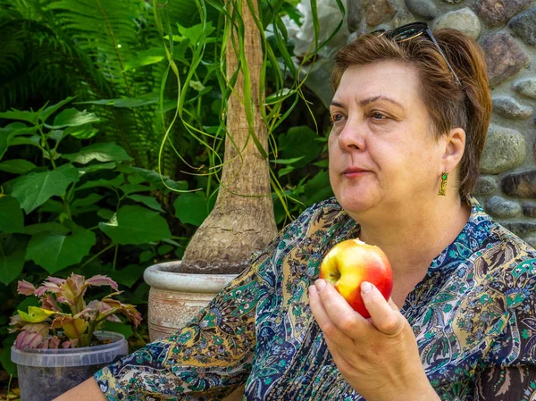 Érett nő pihenő-és eszik egy piros Alma — Stock Fotó