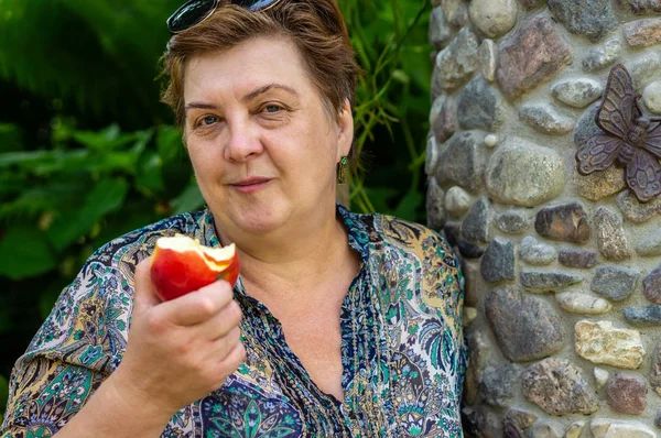 Parkta Olgun kadın ve kırmızı bir Elma yemek