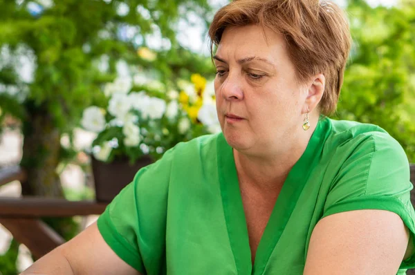 Женщина средних лет в зеленой рубашке отдыхает в городском парке — стоковое фото
