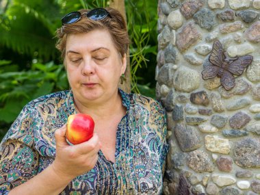 Olgun kadın Parkta istirahat ve kırmızı bir Elma yemek