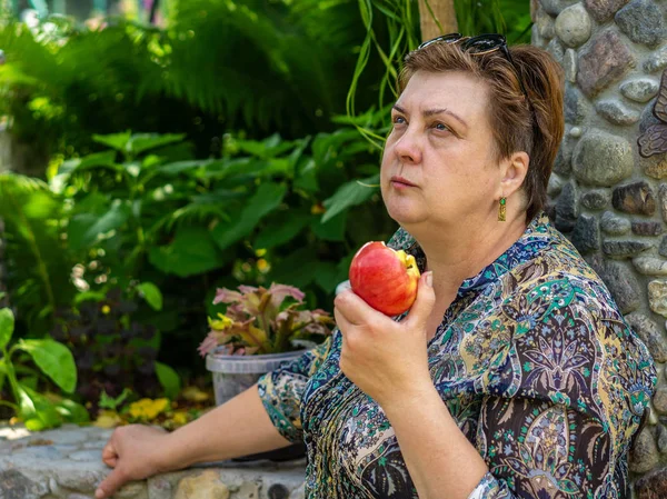 Зрелая женщина ест красное яблоко — стоковое фото