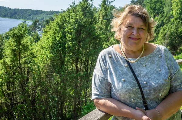 Mogen kvinna vilar i parken vid floden — Stockfoto