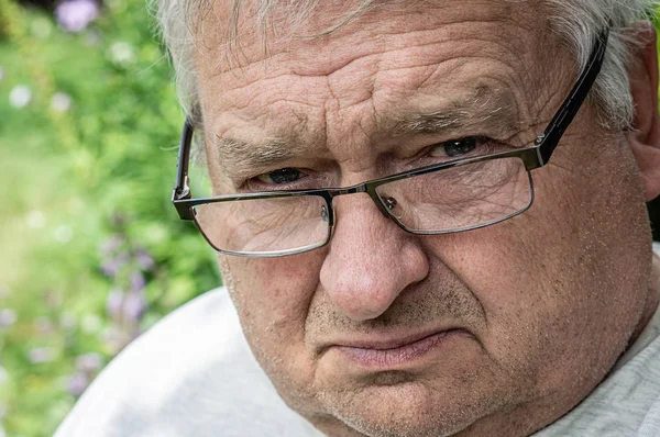 Brooding e arrabbiato vecchio nonno con gli occhiali guarda di fronte o — Foto Stock