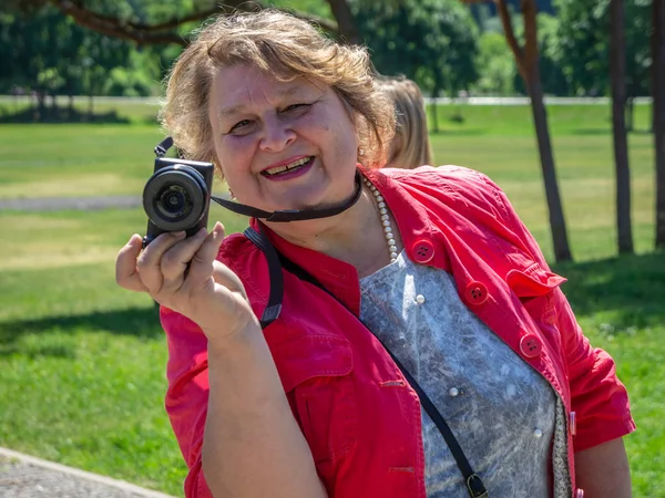 Старуха-туристка в красной куртке с фотоаппаратом, отдыхающая — стоковое фото
