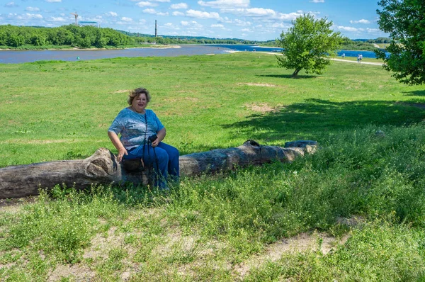 Moden kvinde turist sidder på en log - Stock-foto