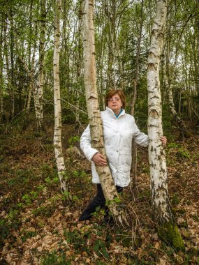 Park'ta dinlenmiş beyaz ceket li ve gözlüklü olgun kadın