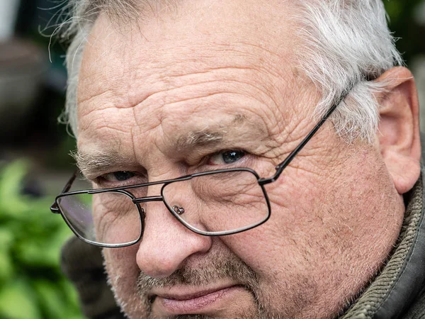 Brooding vieux grand-père non rasé dans des lunettes sales regarde en fron — Photo