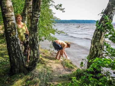 Gölün kıyısında bir kadın, bir çocuk ve bir köpek.