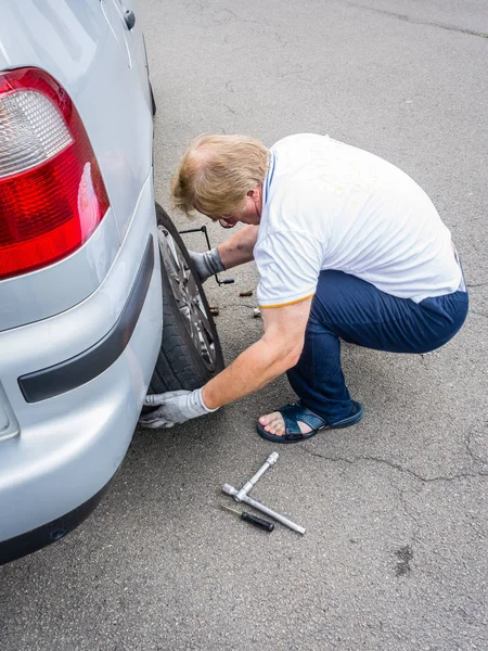 Mature man changes car wheel — Stock Photo, Image