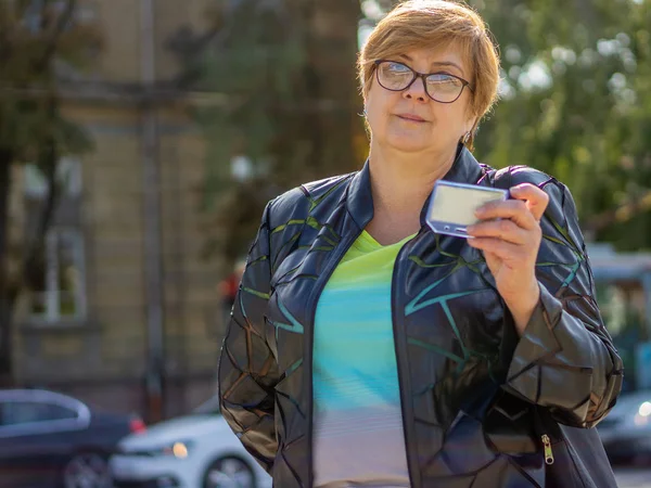 Mogen kvinna med glasögon går gatorna i staden — Stockfoto
