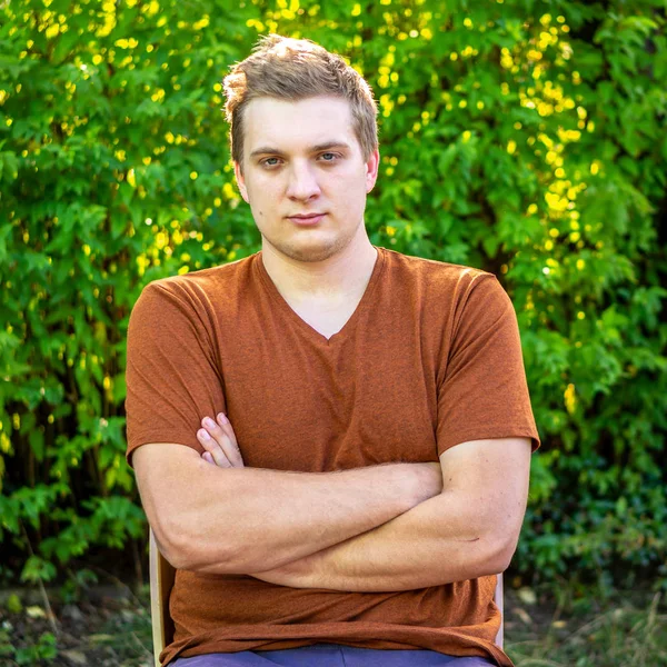 Ein junger Mann in braunem Hemd ruht sich in einem Park aus — Stockfoto