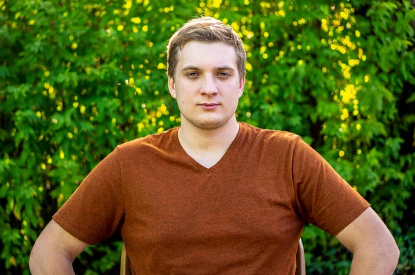 Um jovem com uma camisa marrom está descansando em um parque — Fotografia de Stock