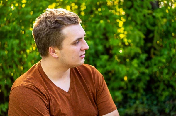 Ein junger Mann im braunen Hemd kommuniziert in einem Park — Stockfoto