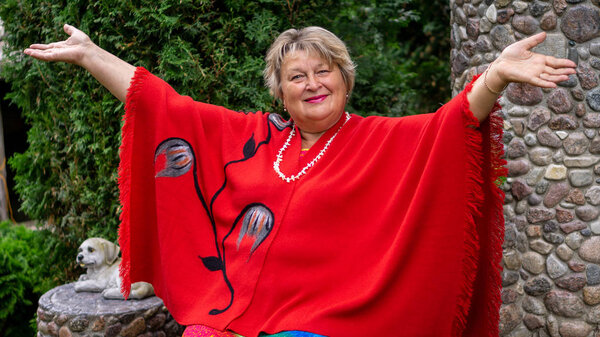 Задумчивая зрелая женщина в красном в городском парке
