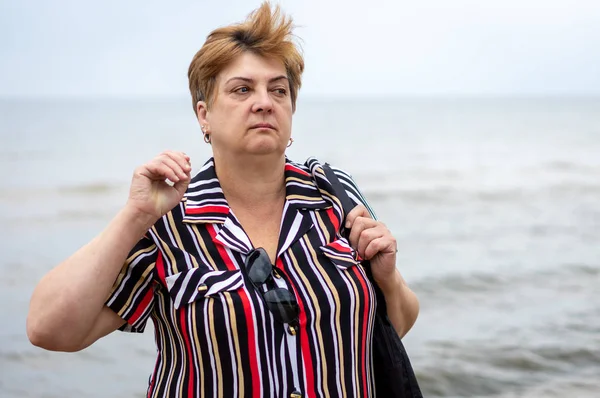 Pensive mogen kvinna i en randig klänning vilar — Stockfoto