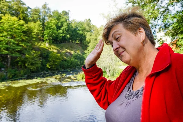 Reife Frau in rotem Pullover, die winkt. Ruhe am Fluss. — Stockfoto