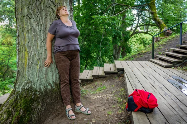 Reife Frau in roter Jacke ruht im Park am Fluss. — Stockfoto