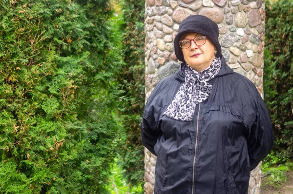 Pensiva donna matura in cappello nero e occhiali a riposo — Foto Stock